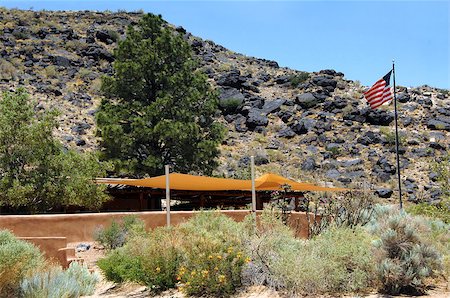Visitor's center, at the Petroglyph National Monument outside of Albuquerque, New Mexico, greets you with American Flag and local floral, canyon and basalt rock formations. Foto de stock - Royalty-Free Super Valor e Assinatura, Número: 400-07824288