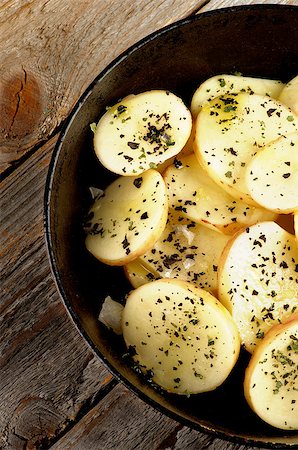 simsearch:400-06485810,k - Wedges of Raw Potato with Basil, Salt and Olive Oil in Black Fry Pan Cross Section on Rustic Wooden background Fotografie stock - Microstock e Abbonamento, Codice: 400-07825321