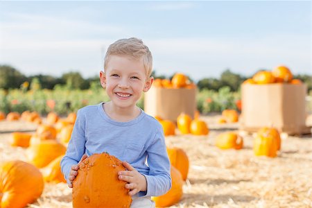 simsearch:400-07211170,k - smiling little boy holding pumpkin while having fun at pumpkin patch at fall Photographie de stock - Aubaine LD & Abonnement, Code: 400-07828243