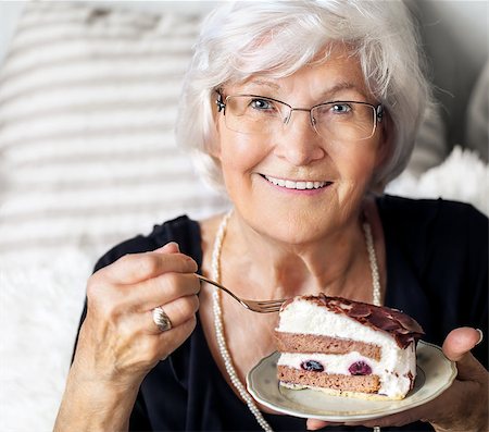 Senior lady looking happy at camera, she likes to eat a piece of creamcake Fotografie stock - Microstock e Abbonamento, Codice: 400-07820113