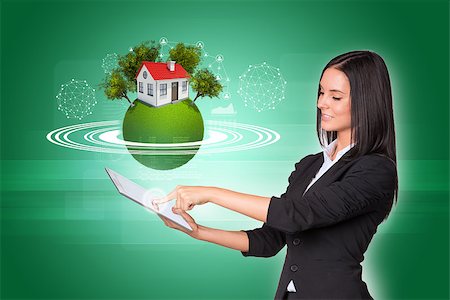 Beautiful businesswomen in suit using digital tablet. Earth with house, trees and wire-frame spheres Stock Photo - Budget Royalty-Free & Subscription, Code: 400-07821847