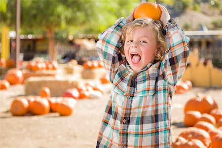 simsearch:400-07179959,k - Adorable Little Boy Sitting and Holding His Pumpkin in a Rustic Ranch Setting at the Pumpkin Patch. Stockbilder - Microstock & Abonnement, Bildnummer: 400-07821886