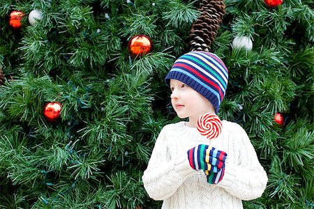 silly winter boy - cute little boy holding candy by the christmas tree Stock Photo - Budget Royalty-Free & Subscription, Code: 400-07822525