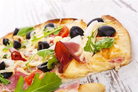 simsearch:400-04302812,k - Delicious colorful pizza with tomatoes, melted cheese, black olives, onions, ham and fresh herbs on white wooden background. Culinary mediterranean pizza eating. Fotografie stock - Microstock e Abbonamento, Codice: 400-07822664