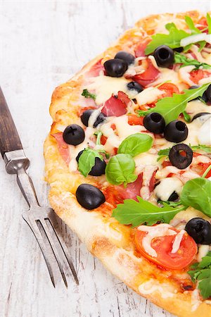 simsearch:400-04302812,k - Delicious colorful pizza with tomatoes, melted cheese, black olives, onions, ham and fresh herbs on white wooden background. Culinary mediterranean pizza eating. Fotografie stock - Microstock e Abbonamento, Codice: 400-07822665