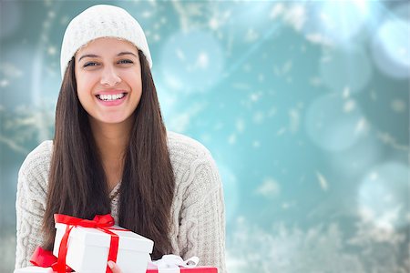 simsearch:400-07834588,k - Festive brunette holding gifts against blurred christmas background Fotografie stock - Microstock e Abbonamento, Codice: 400-07834027