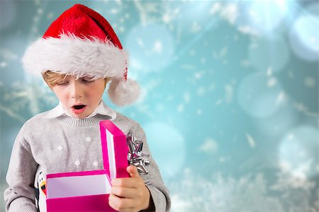 simsearch:400-07834588,k - Festive boy holding a gift against blurred christmas background Fotografie stock - Microstock e Abbonamento, Codice: 400-07834034