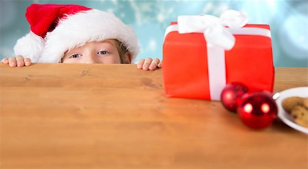 Festive boy peeking over table against blurred christmas background Stock Photo - Budget Royalty-Free & Subscription, Code: 400-07834035