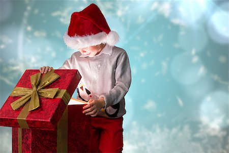 simsearch:400-07834588,k - Festive boy opening gift against blurred christmas background Fotografie stock - Microstock e Abbonamento, Codice: 400-07834033