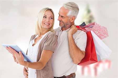 Happy couple with shopping bags and tablet pc against blurry christmas tree in room Stock Photo - Budget Royalty-Free & Subscription, Code: 400-07834145