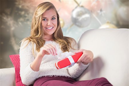 simsearch:400-07834588,k - Pretty blonde opening a gift against blurred christmas background Fotografie stock - Microstock e Abbonamento, Codice: 400-07834170