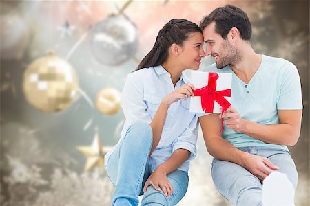 simsearch:400-07834588,k - Young couple holding gift against blurred christmas background Fotografie stock - Microstock e Abbonamento, Codice: 400-07834186
