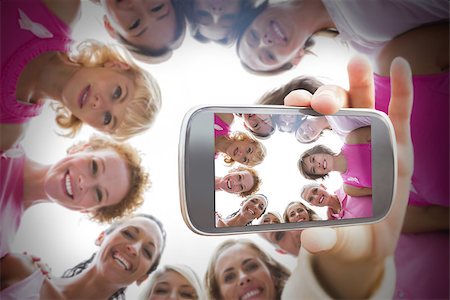 Composite image of hand holding smartphone showing photograph of breast cancer activists Foto de stock - Super Valor sin royalties y Suscripción, Código: 400-07834622