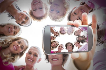 simsearch:400-06932887,k - Composite image of hand holding smartphone showing photograph of breast cancer activists Fotografie stock - Microstock e Abbonamento, Codice: 400-07834623