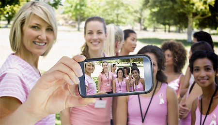 Composite image of hand holding smartphone showing photograph of breast cancer activists Foto de stock - Super Valor sin royalties y Suscripción, Código: 400-07834638