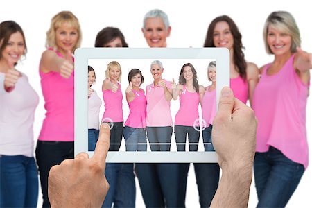 Composite image of hand holding tablet pc showing photograph of breast cancer activists Foto de stock - Super Valor sin royalties y Suscripción, Código: 400-07834674