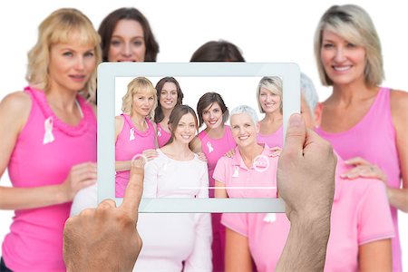 Composite image of hand holding tablet pc showing photograph of breast cancer activists Foto de stock - Super Valor sin royalties y Suscripción, Código: 400-07834676