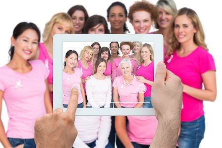 Composite image of hand holding tablet pc showing photograph of breast cancer activists Foto de stock - Super Valor sin royalties y Suscripción, Código: 400-07834671