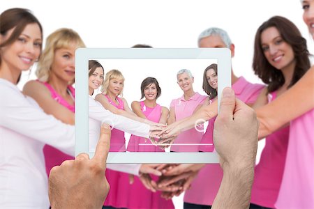 Composite image of hand holding tablet pc showing photograph of breast cancer activists Foto de stock - Super Valor sin royalties y Suscripción, Código: 400-07834672