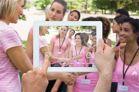 Composite image of hand holding device showing photograph of breast cancer activists Foto de stock - Super Valor sin royalties y Suscripción, Código: 400-07834699