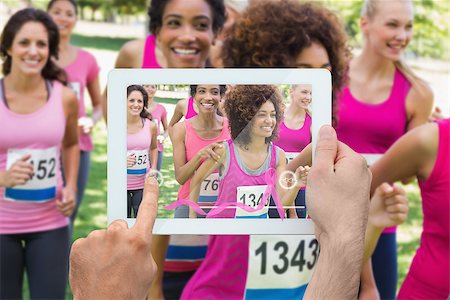 Composite image of hand holding device showing photograph of breast cancer activists Foto de stock - Super Valor sin royalties y Suscripción, Código: 400-07834692