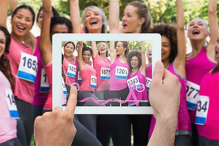 Composite image of hand holding device showing photograph of breast cancer activists Foto de stock - Super Valor sin royalties y Suscripción, Código: 400-07834707