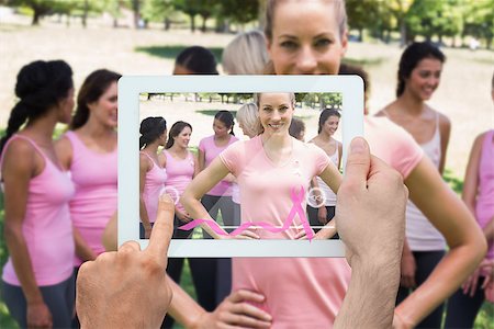 Composite image of hand holding device showing photograph of breast cancer activists Foto de stock - Super Valor sin royalties y Suscripción, Código: 400-07834700