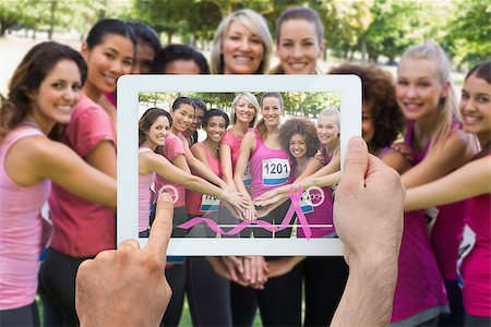 Composite image of hand holding device showing photograph of breast cancer activists Foto de stock - Super Valor sin royalties y Suscripción, Código: 400-07834701