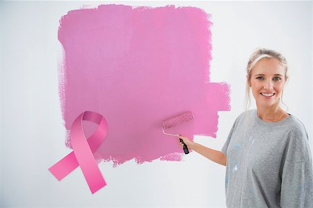 simsearch:400-07834992,k - Happy young woman painting her wall pink against pink breast cancer awareness ribbon Fotografie stock - Microstock e Abbonamento, Codice: 400-07834978