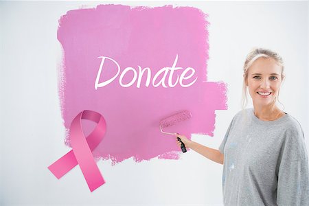 simsearch:400-07834992,k - Happy young woman painting her wall pink against pink breast cancer awareness ribbon Fotografie stock - Microstock e Abbonamento, Codice: 400-07834985