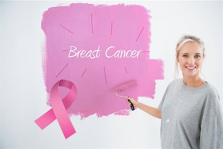 simsearch:400-07834992,k - Happy young woman painting her wall pink against pink breast cancer awareness ribbon Fotografie stock - Microstock e Abbonamento, Codice: 400-07834986