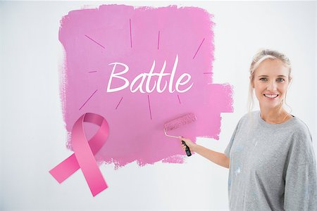 simsearch:400-07834992,k - Happy young woman painting her wall pink against pink breast cancer awareness ribbon Fotografie stock - Microstock e Abbonamento, Codice: 400-07834988