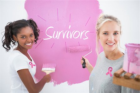 simsearch:400-07834992,k - Smiling housemates painting wall pink against pink breast cancer awareness ribbon Fotografie stock - Microstock e Abbonamento, Codice: 400-07834995