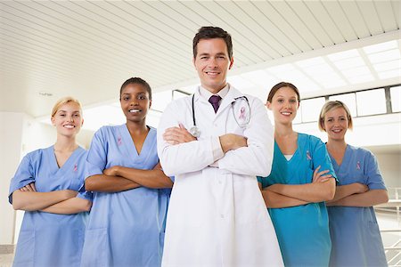 simsearch:400-06800658,k - Smiling doctor and nurses with arms crossed wearing breast cancer awareness ribbon Stock Photo - Budget Royalty-Free & Subscription, Code: 400-07835170