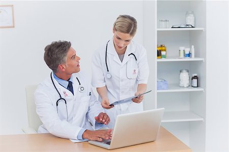 Nurse showing a folder to her colleague wearing breast cancer awareness ribbon Photographie de stock - Aubaine LD & Abonnement, Code: 400-07835183