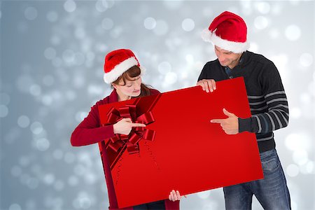 Couple holding a sign with red christmas ribbon Stock Photo - Budget Royalty-Free & Subscription, Code: 400-07835353