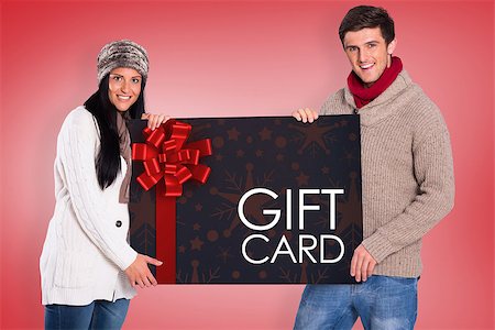 simsearch:400-07834588,k - Young couple holding a poster against gift card with festive bow Fotografie stock - Microstock e Abbonamento, Codice: 400-07835373
