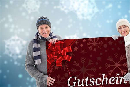 simsearch:400-07834588,k - Winter couple showing poster against gift card with festive bow Fotografie stock - Microstock e Abbonamento, Codice: 400-07835391