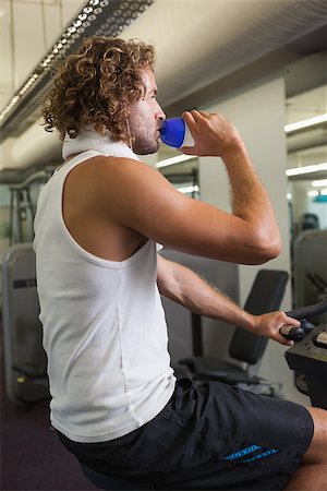 simsearch:400-04027186,k - Side view of a young man drinking water on exercise bike at the gym Stockbilder - Microstock & Abonnement, Bildnummer: 400-07839189