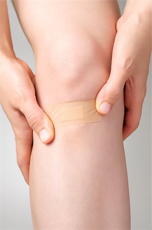 simsearch:400-07831838,k - Woman putting an adhesive bandage on her leg Foto de stock - Royalty-Free Super Valor e Assinatura, Número: 400-07830736
