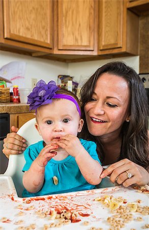 Mother in messy kitchen smiles as baby eats Stock Photo - Budget Royalty-Free & Subscription, Code: 400-07833268
