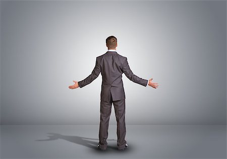 Businessman in suit standing in an empty gray room. Rear view. Spread your arms to side Stock Photo - Budget Royalty-Free & Subscription, Code: 400-07894681