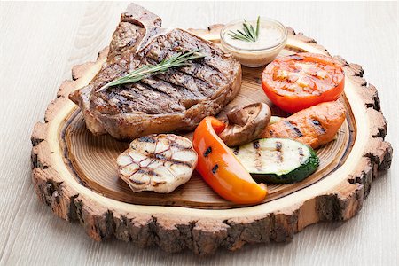 Portion of BBQ t-bone steak  served  on wooden board with  rosemary, mustard sauce  and grilled vegetables : tomato, carrot, paprika, garlic,  champignon,  zucchini Stock Photo - Budget Royalty-Free & Subscription, Code: 400-07895244