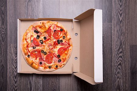 simsearch:400-05682309,k - Italian pizza with ham, tomatoes, and olives in box, on gray table background Stock Photo - Budget Royalty-Free & Subscription, Code: 400-07895473