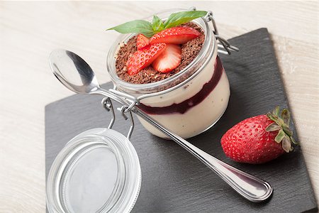 Delicious traditional italian cream dessert pannacotta with grated chocolate, strawberry, and basil served in jar with cocktail spoon on black stone background Stock Photo - Budget Royalty-Free & Subscription, Code: 400-07896192