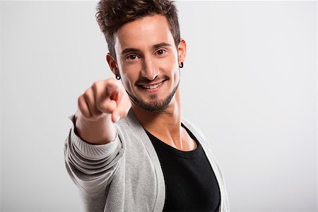 Handsome young man looking and pointing to the camera, over a gray background Stock Photo - Budget Royalty-Free & Subscription, Code: 400-07896602
