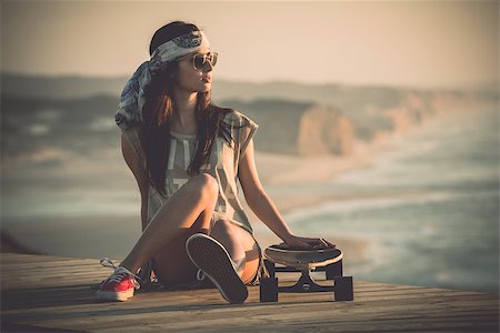 Beautiful young woman sitting over a skateboard Stock Photo - Budget Royalty-Free & Subscription, Code: 400-07896629