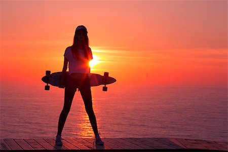 Beautiful and fashion young woman posing at teh sunset with a skateboard Stock Photo - Budget Royalty-Free & Subscription, Code: 400-07896633