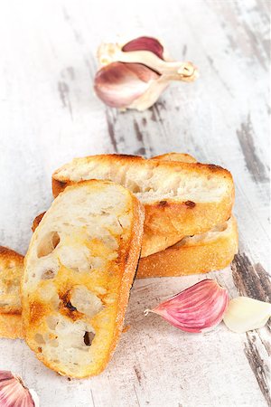 simsearch:400-06096133,k - Garlic baguette with fresh garlic on white wooden textured background. Culinary eating, french country style. Fotografie stock - Microstock e Abbonamento, Codice: 400-07896935