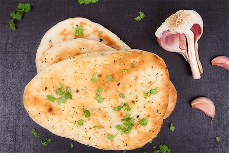 Naan bread with fresh parsley herb and garlic on black background top view. Culinary indian and eastern cuisine. Foto de stock - Super Valor sin royalties y Suscripción, Código: 400-07896940